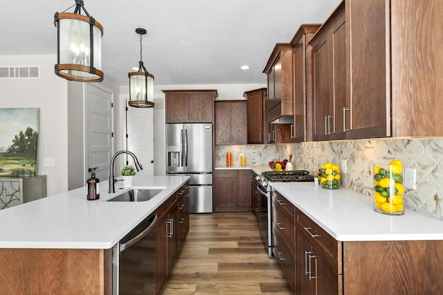 kitchen featuring light countertops, appliances with stainless steel finishes, an island with sink, and a sink