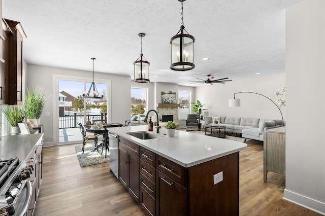 kitchen with an island with sink, appliances with stainless steel finishes, hanging light fixtures, light countertops, and a sink