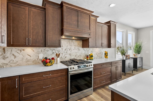 kitchen with light countertops, premium range hood, and stainless steel gas range