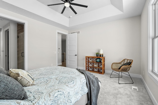 bedroom with carpet floors, a raised ceiling, visible vents, and baseboards