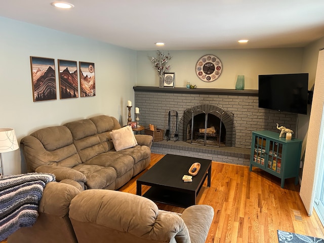 living room with wood-type flooring and a brick fireplace