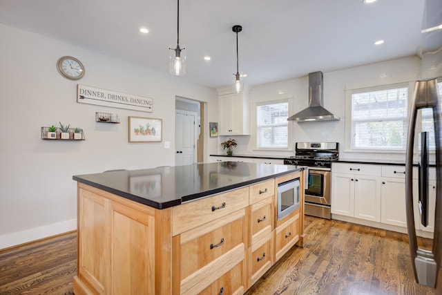 kitchen featuring stainless steel appliances, wall chimney range hood, dark hardwood / wood-style flooring, pendant lighting, and white cabinets