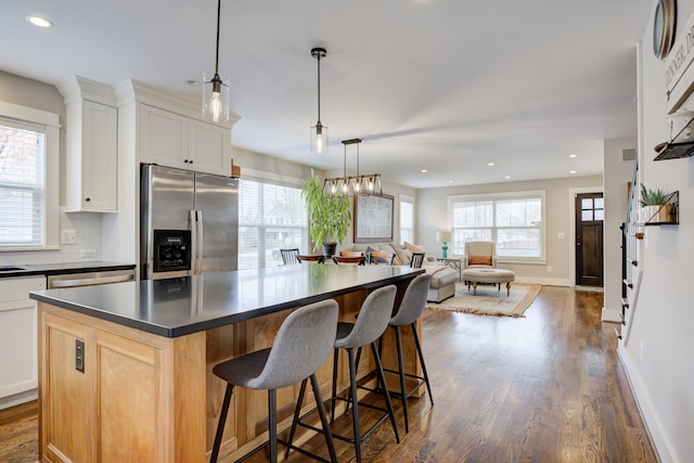 kitchen featuring a wealth of natural light, stainless steel fridge, white cabinets, and a kitchen island