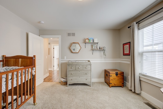 bedroom featuring light carpet and a nursery area