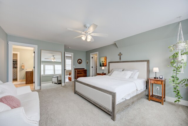 bedroom with ceiling fan, light colored carpet, and ensuite bath