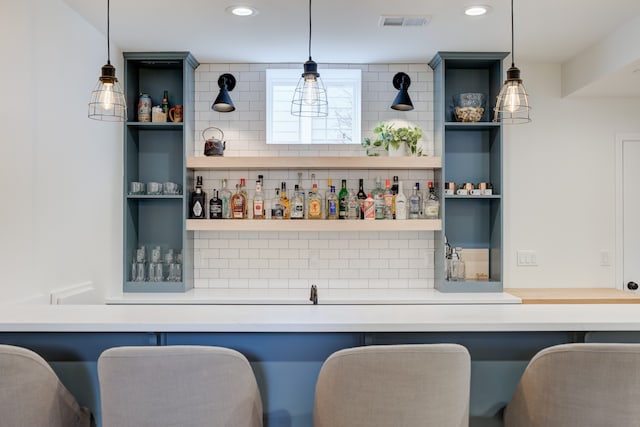 bar featuring decorative light fixtures and backsplash