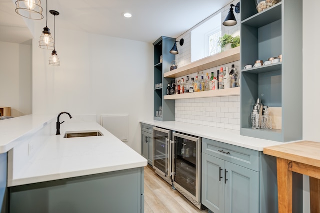 kitchen with sink, beverage cooler, kitchen peninsula, pendant lighting, and light hardwood / wood-style floors