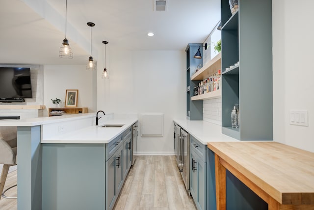 kitchen featuring sink, hanging light fixtures, tasteful backsplash, kitchen peninsula, and light wood-type flooring