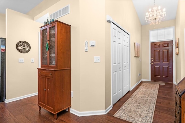 foyer entrance with dark hardwood / wood-style flooring and a chandelier