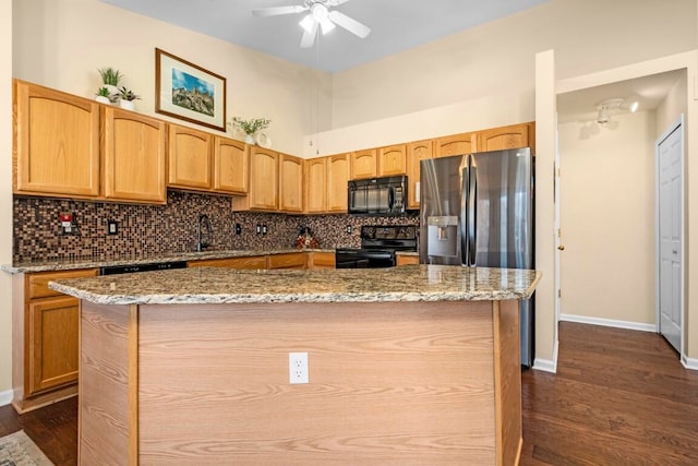 kitchen with dark wood-type flooring, stone counters, a center island, and black appliances