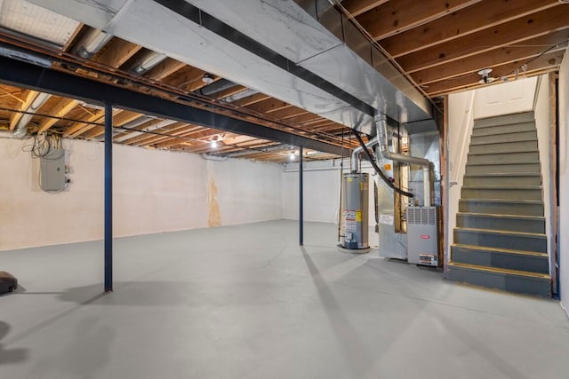 basement featuring electric panel, heating unit, and water heater