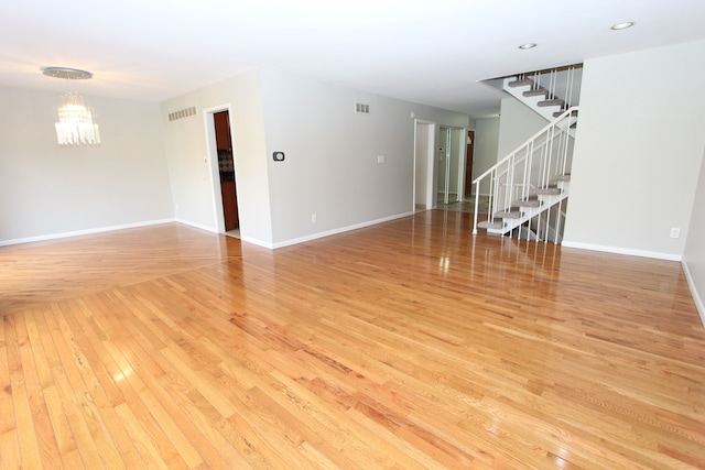 unfurnished living room with a chandelier and light wood-type flooring