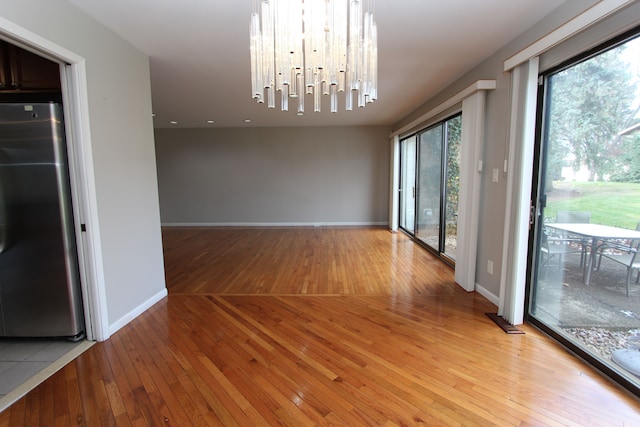 unfurnished dining area featuring a notable chandelier and light hardwood / wood-style flooring