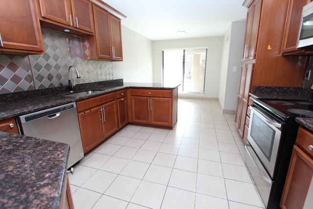 kitchen with sink, stainless steel appliances, dark stone counters, and tasteful backsplash