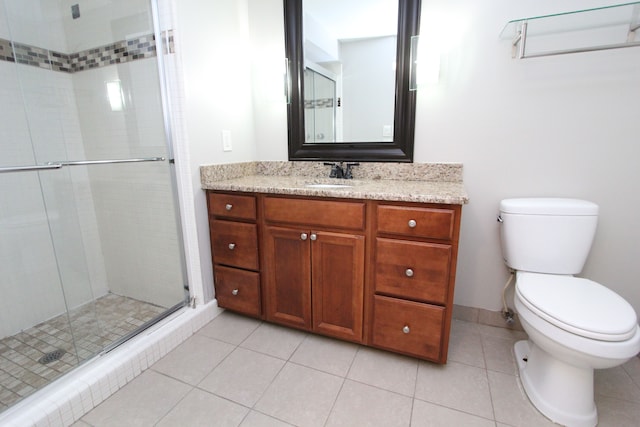 bathroom with tile patterned floors, vanity, a shower with shower door, and toilet