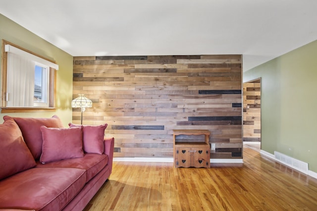 living room with light wood-type flooring and wooden walls