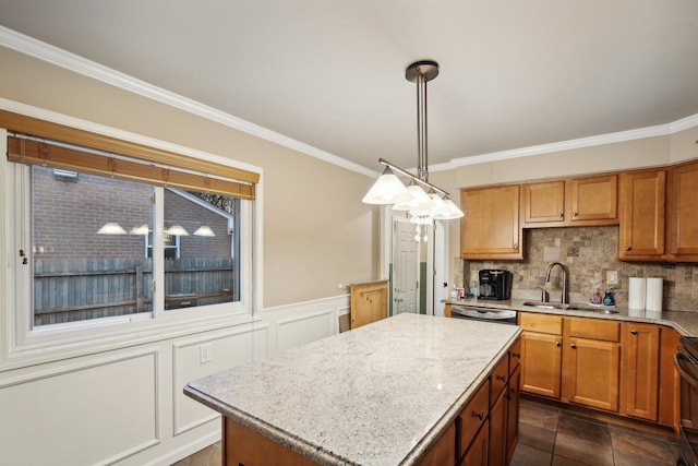 kitchen with a center island, sink, hanging light fixtures, ornamental molding, and tasteful backsplash