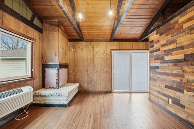 unfurnished room featuring a wall mounted air conditioner, wood ceiling, vaulted ceiling with beams, light hardwood / wood-style floors, and wood walls