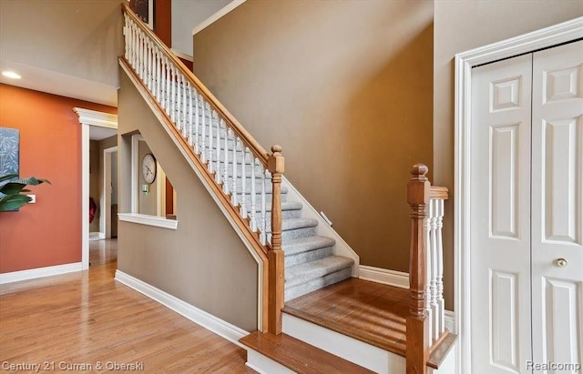 stairway with decorative columns and wood-type flooring