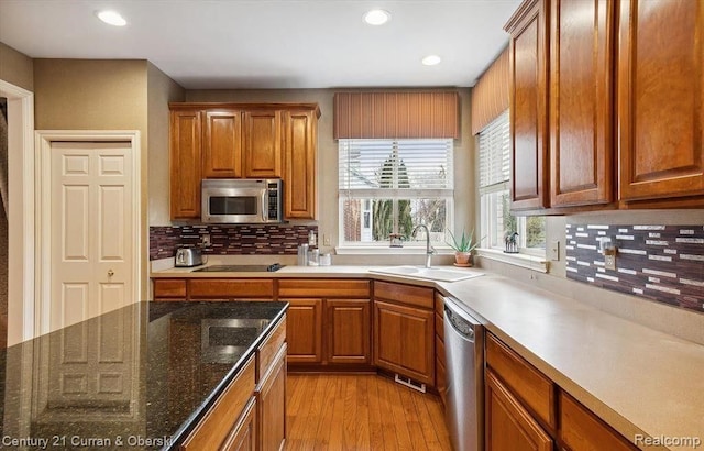 kitchen with appliances with stainless steel finishes, tasteful backsplash, light hardwood / wood-style flooring, and sink