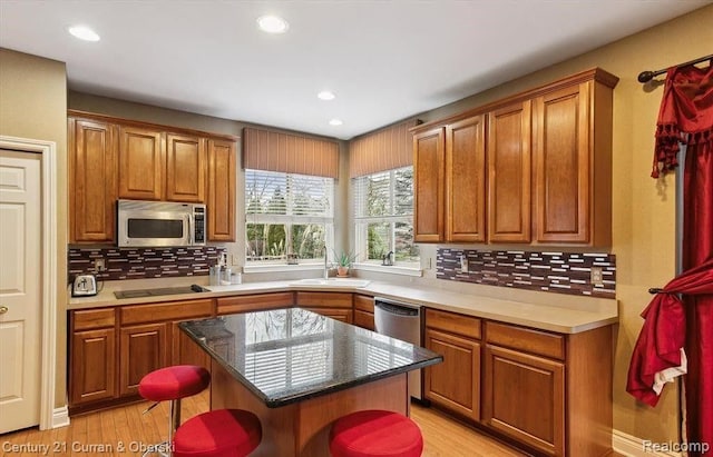 kitchen featuring decorative backsplash, light hardwood / wood-style floors, a kitchen breakfast bar, and appliances with stainless steel finishes