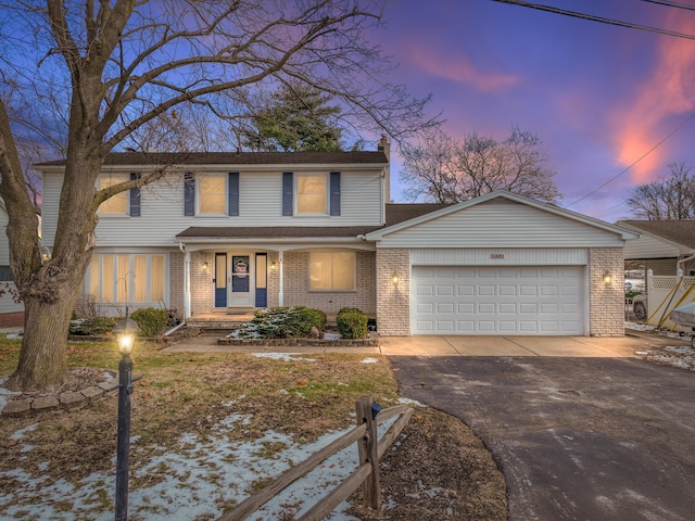 traditional home featuring brick siding, driveway, a chimney, and an attached garage