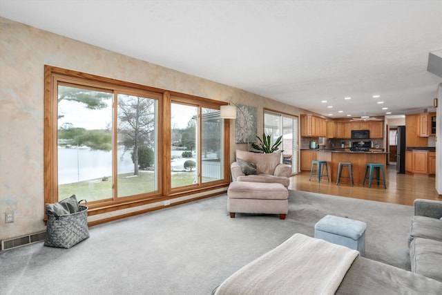 living room with light carpet and a water view