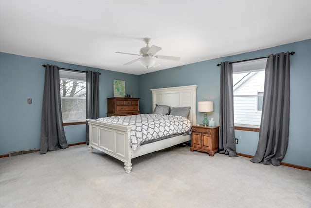 bedroom with baseboards, ceiling fan, visible vents, and light colored carpet