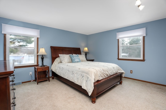 bedroom featuring multiple windows, baseboards, and light colored carpet