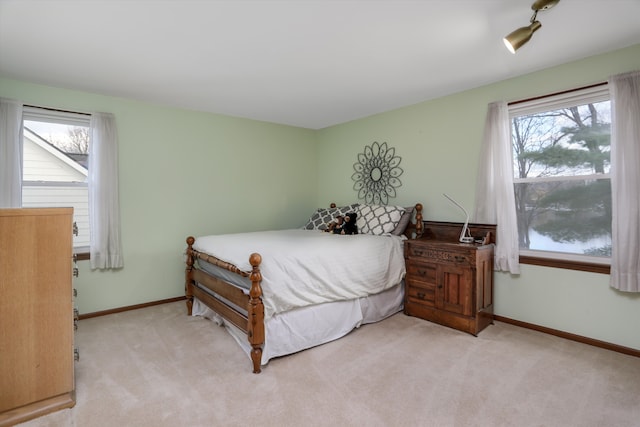 bedroom with light carpet, multiple windows, and baseboards