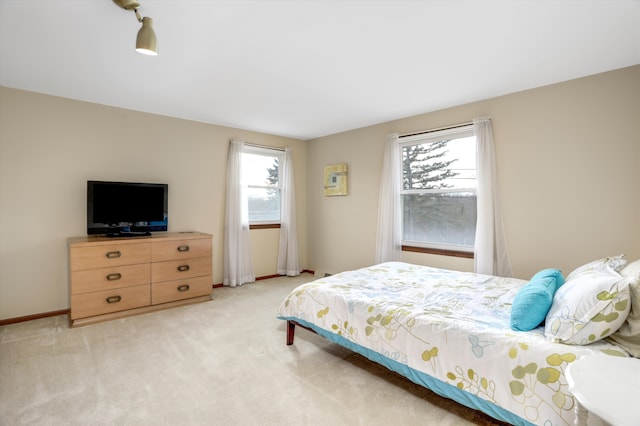 bedroom with multiple windows, baseboards, and light colored carpet