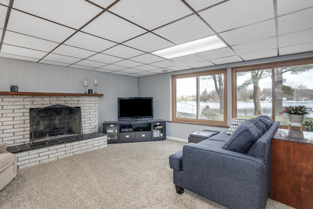 carpeted living area featuring a drop ceiling, a brick fireplace, and baseboards