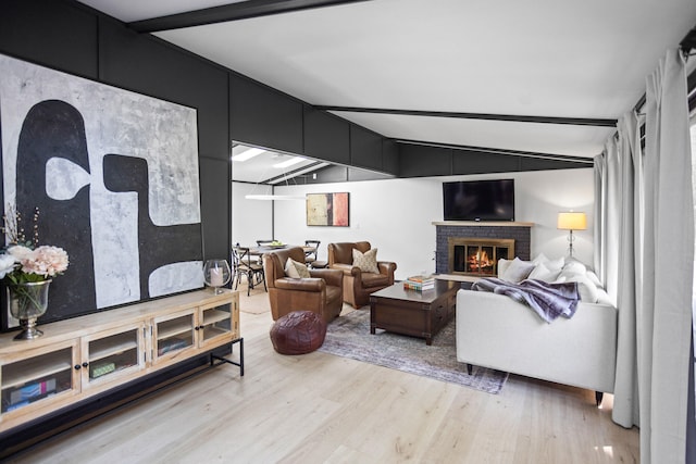 living room with lofted ceiling with beams, a fireplace, and light hardwood / wood-style flooring