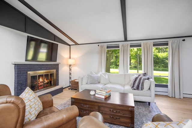 living room featuring plenty of natural light, lofted ceiling with beams, light wood-type flooring, and a brick fireplace