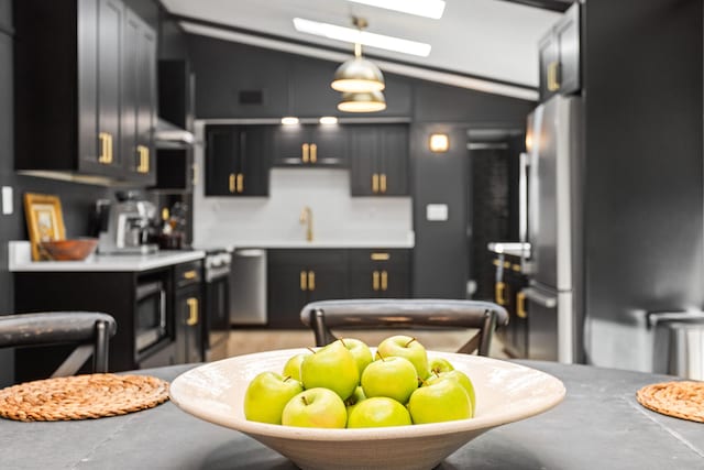 kitchen with ventilation hood, sink, lofted ceiling, and hanging light fixtures