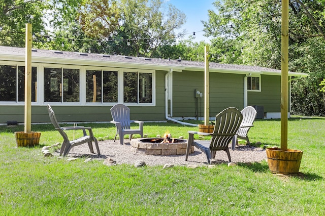 back of property with a lawn, central AC, and an outdoor fire pit