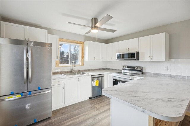 kitchen with white cabinets, appliances with stainless steel finishes, light hardwood / wood-style flooring, and sink