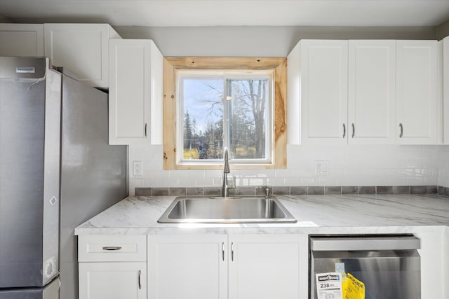 kitchen with stainless steel fridge, backsplash, dishwashing machine, sink, and white cabinetry