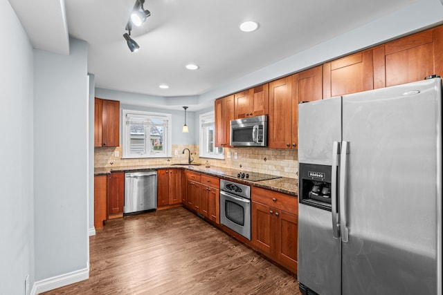 kitchen with pendant lighting, decorative backsplash, dark stone countertops, dark hardwood / wood-style flooring, and stainless steel appliances