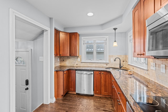 kitchen featuring sink, dark hardwood / wood-style flooring, backsplash, pendant lighting, and appliances with stainless steel finishes