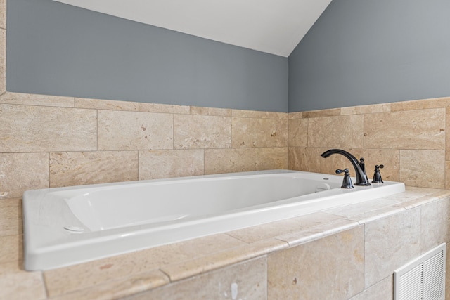 bathroom with tiled bath and lofted ceiling