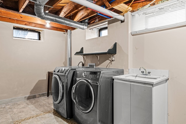 washroom featuring a healthy amount of sunlight, washing machine and dryer, and sink