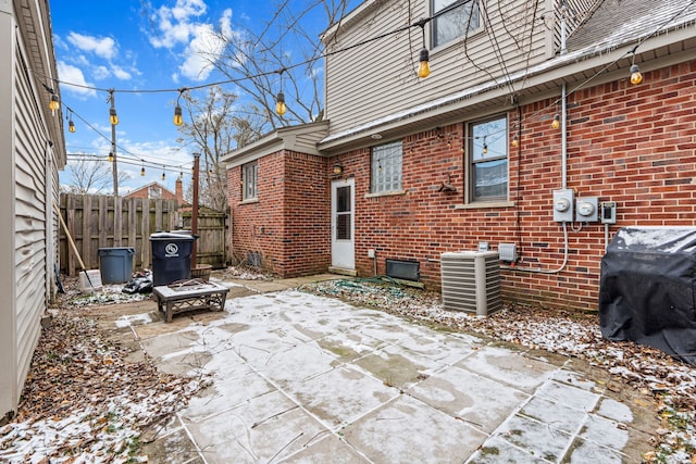 snow covered patio featuring grilling area, cooling unit, and an outdoor fire pit