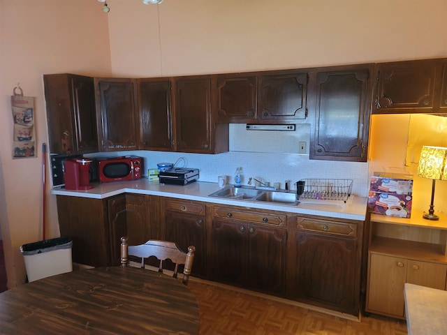 kitchen featuring dark brown cabinetry, sink, and tasteful backsplash