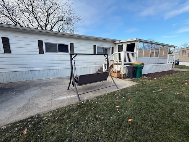 rear view of property with a lawn, a sunroom, and a patio