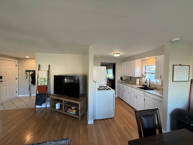 kitchen featuring white appliances, light wood-type flooring, white cabinetry, and sink