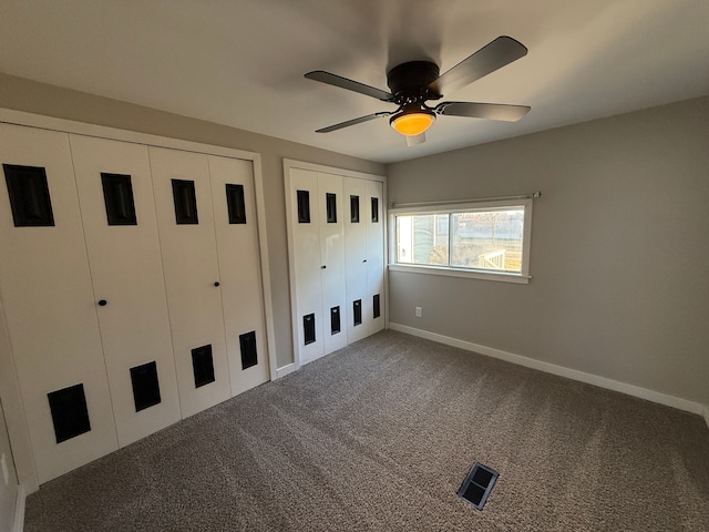 unfurnished bedroom with carpet flooring, ceiling fan, and two closets