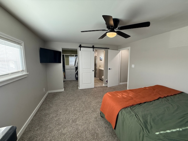 bedroom featuring carpet, a barn door, ensuite bathroom, and ceiling fan