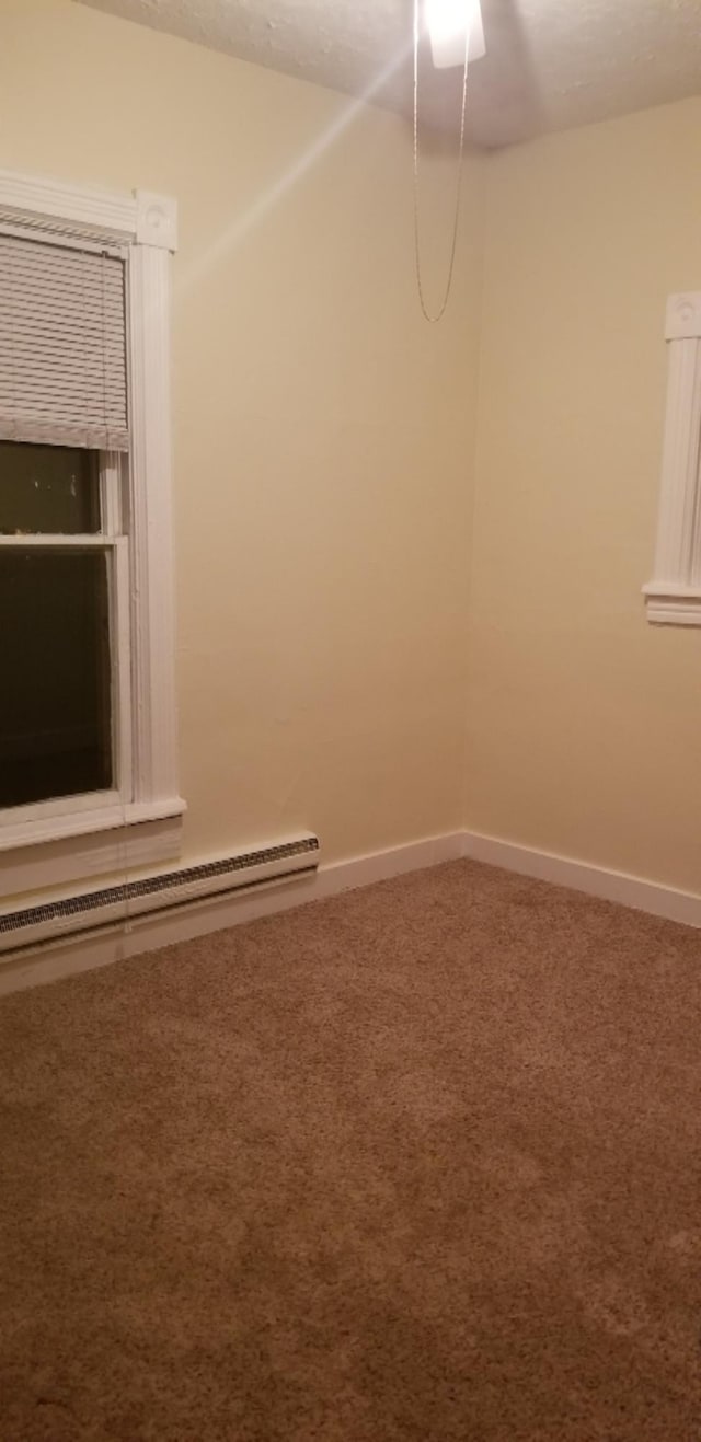 carpeted spare room with a baseboard radiator