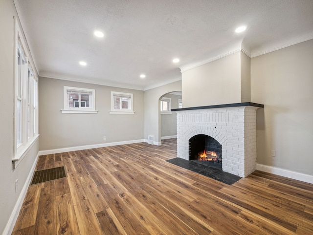 unfurnished living room with a fireplace, a textured ceiling, hardwood / wood-style flooring, and ornamental molding